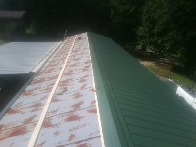 Old rusted panels beside newly installed green metal roofing — Wind Damage Roof Repair by Roofing Brothers in Chestnut Mound