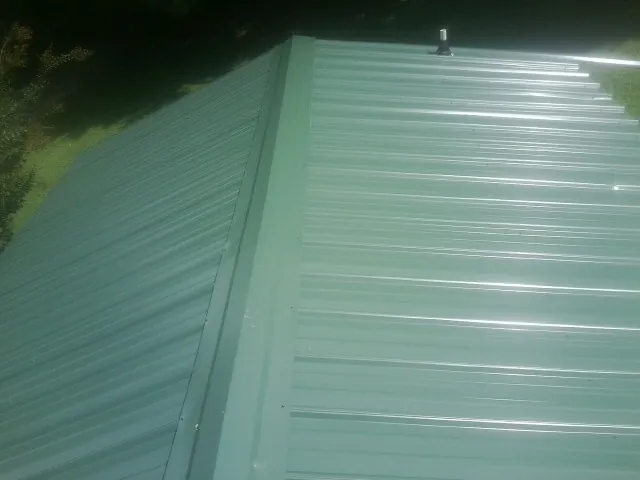 New green metal panels meeting at the ridge of a roof — Flat Roof Repair work by our crew in Chestnut Mound