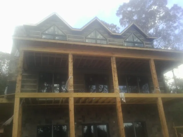 Dormers and porch framing on a large log home under construction — Roof Coating work by our crew in Chestnut Mound