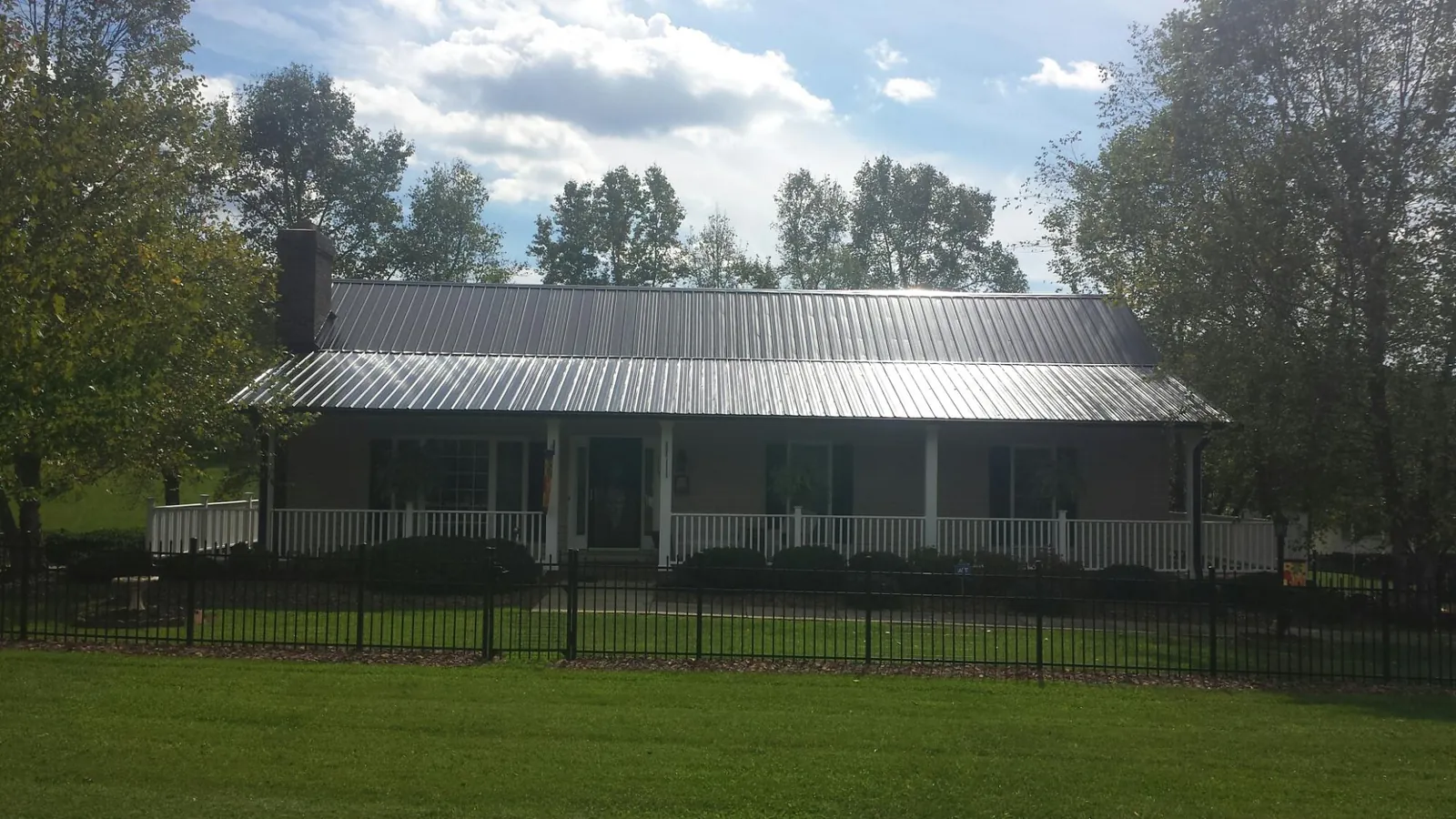 Gray metal roof on a brick ranch with a full width front porch — Gutter Guard Installation work by our crew in Chestnut Mound