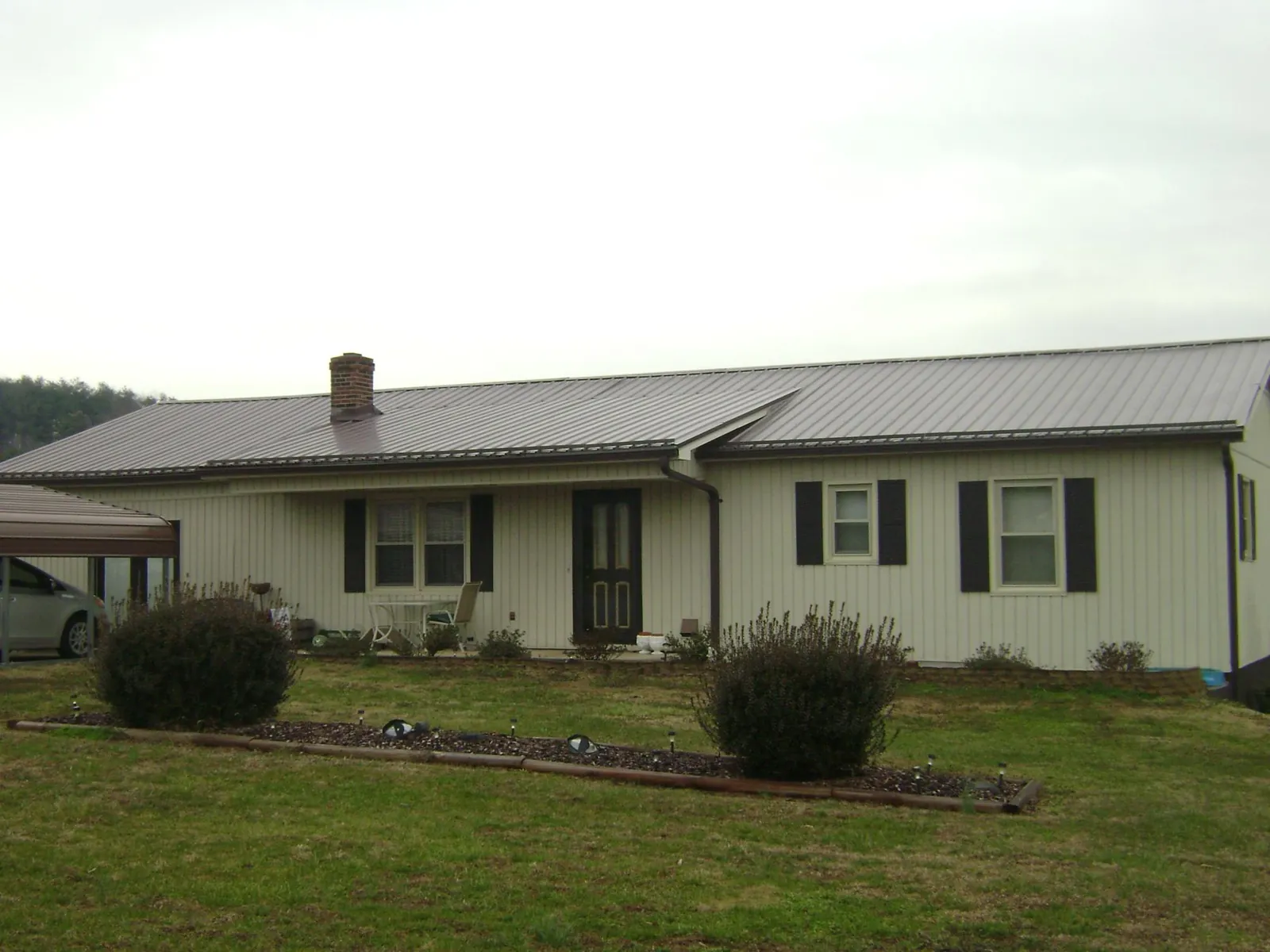 Brown metal roof on a cream sided ranch home with a brick chimney in Chestnut Mound