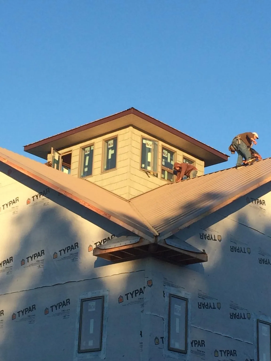 Roofers working around a rooftop cupola on a new metal roof at sunset — Roof Waterproofing in Chestnut Mound by Roofing Brothers